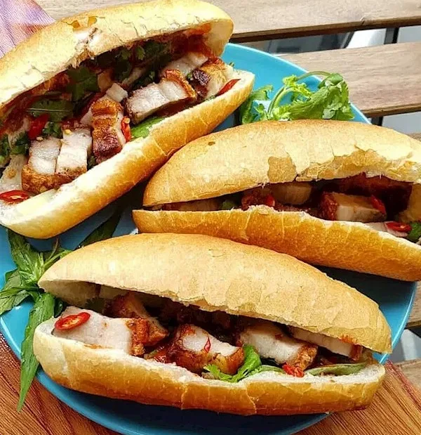 Vietnamese banh mi sandwich filled with crispy roast pork, cilantro, cucumber, and sliced chile