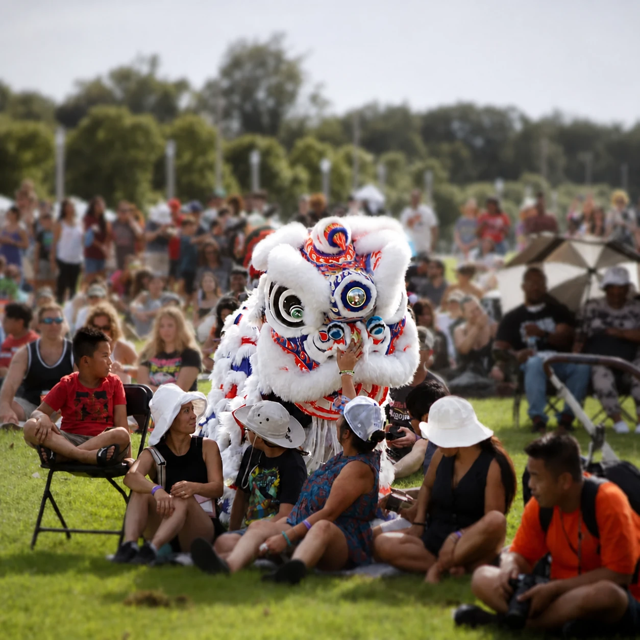 Lion dance performer greeting families seated on the festival lawn