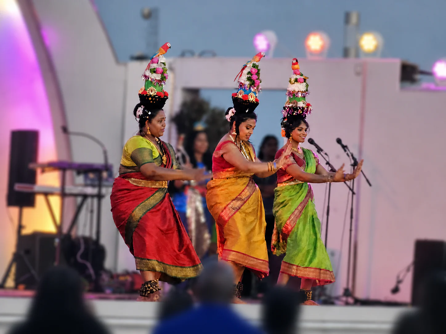 Indian folk dancers performing with decorated pots under stage lights