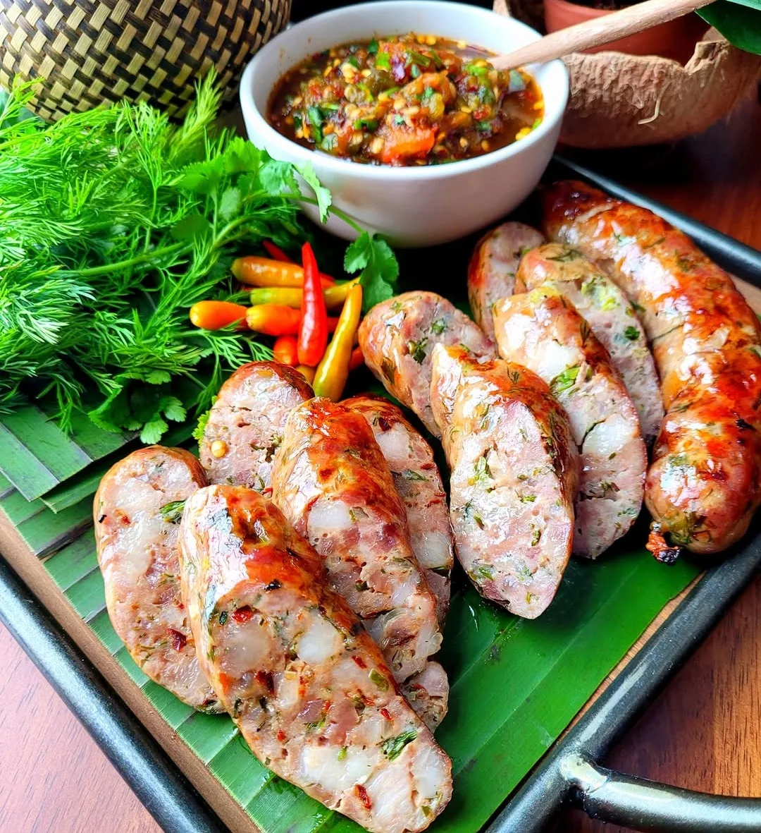 Sliced Lao sausage with fresh herbs, chiles, and a spicy dipping sauce