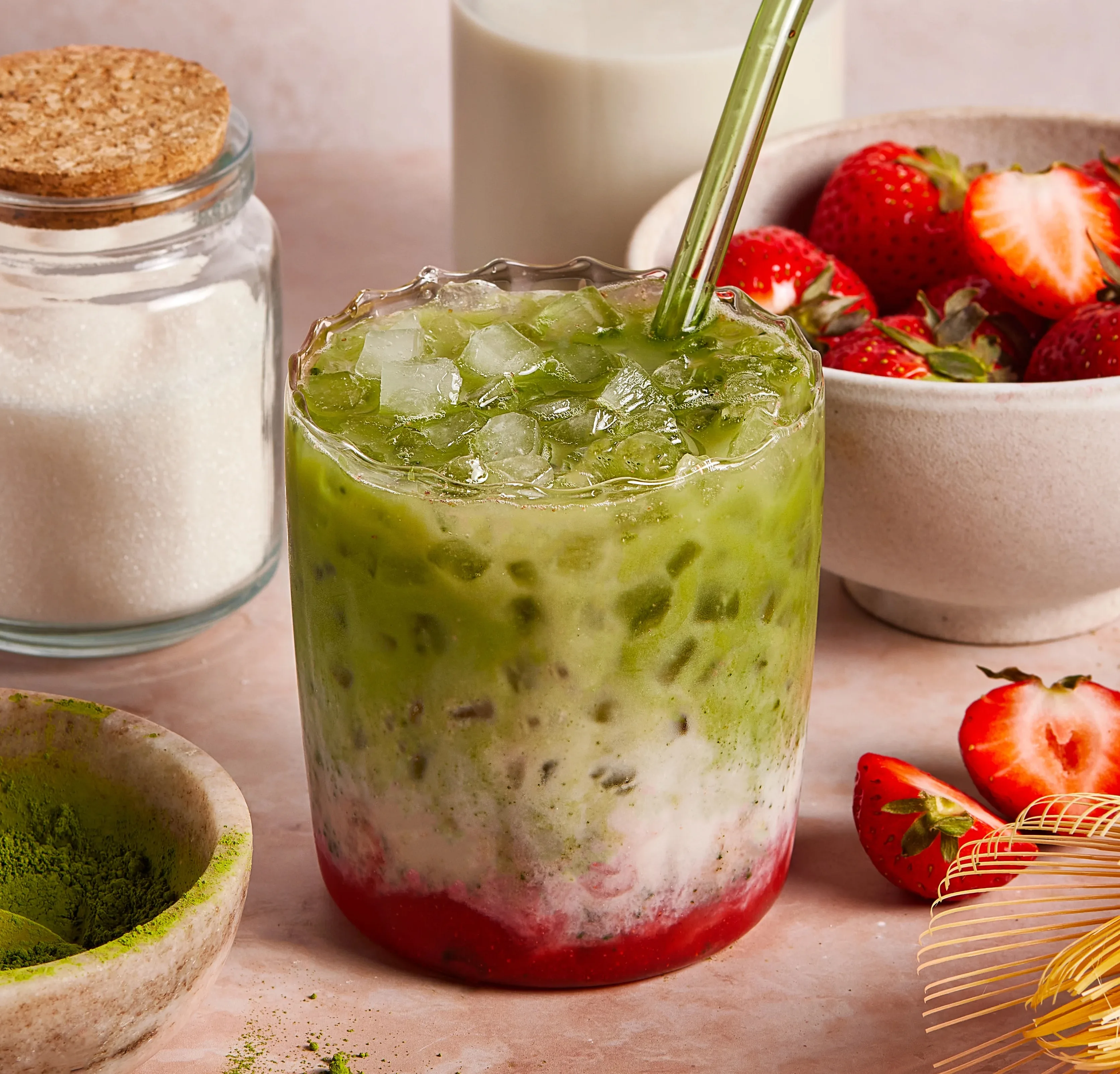 Iced strawberry matcha latte layered with milk and served with fresh strawberries