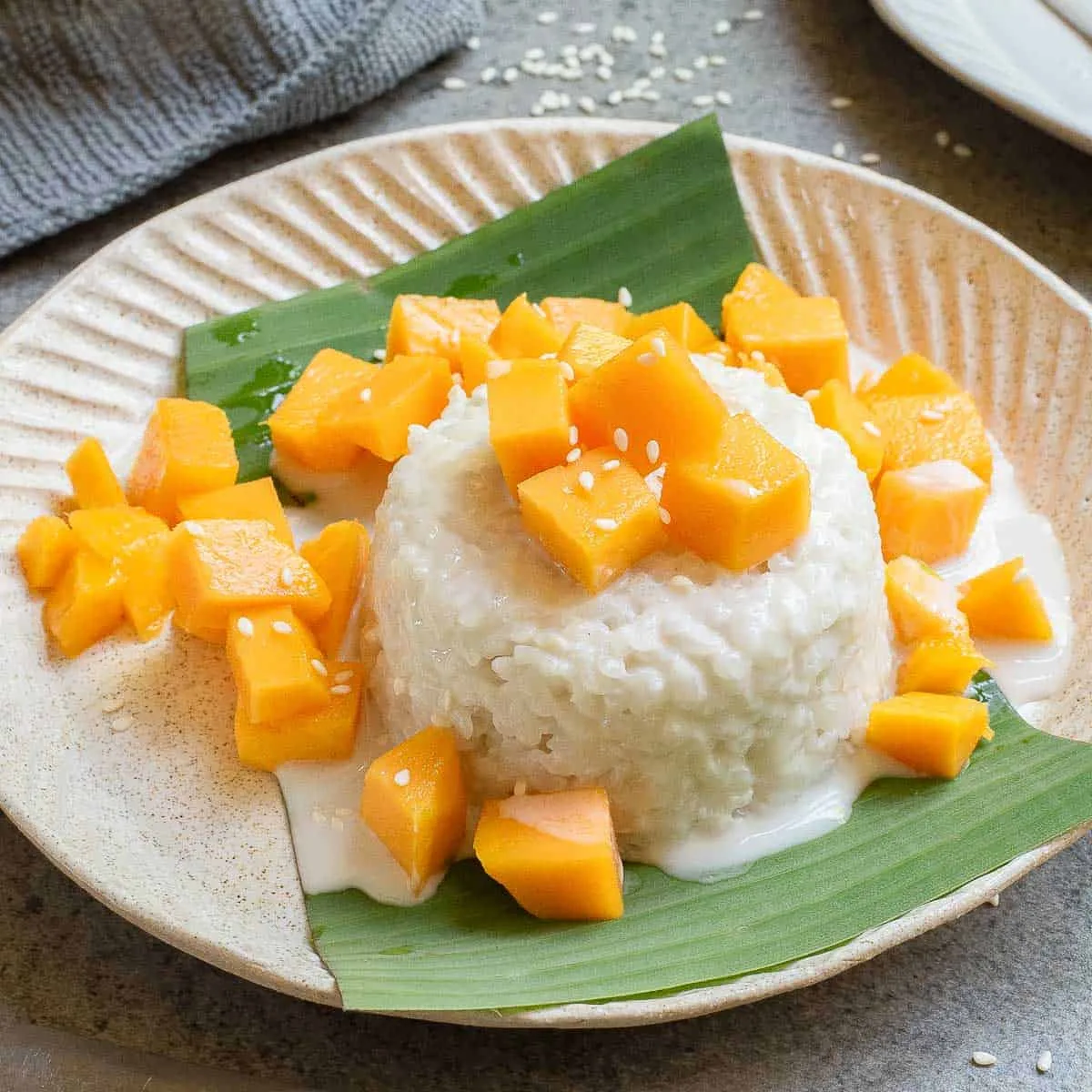 Thai mango sticky rice with coconut cream and fresh mango on a banana leaf